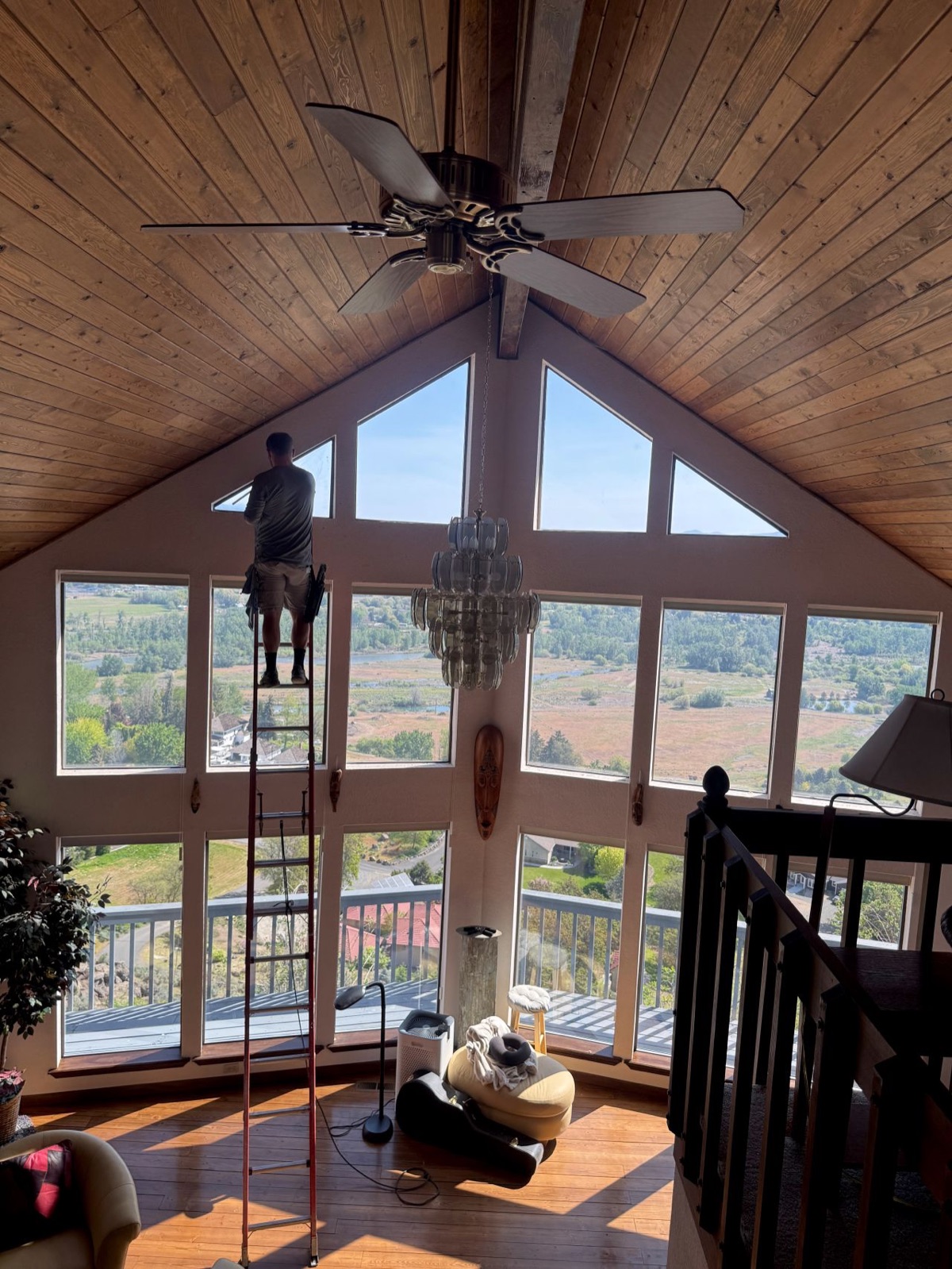 Cleaning a wall of vaulted windows in a Yakima Valley home with a valley view.